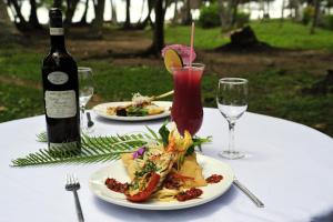 a table with two plates of food and a bottle of wine at Ankobra Beach Resort in Axim +46 photos