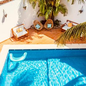 a blue swimming pool with chairs and a palm tree at Enigmatic Hotel Experience in Cancún