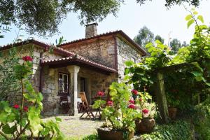 a small stone house with flowers in front of it at Casa da Ramada, Turismo Espaço rural. in Ponte de Lima