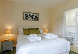 a bedroom with a white bed with towels on it at Oak Cottage in Dulverton
