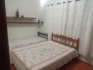 two twin beds in a room with curtains at Casa Lá Vita in Uberaba