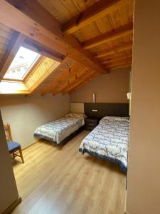 a bedroom with two beds and a wooden ceiling at PENSION CASA MIÑO in Pola de Somiedo