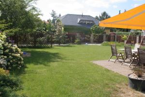einen Garten mit Stühlen und einem orangenen Regenschirm in der Unterkunft Holiday Home Prague Pruhonice in Pruhonice