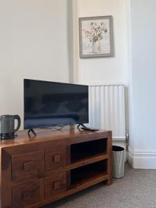 a flat screen tv sitting on top of a wooden entertainment center at Ensuite Double Room, by Swansea University, Sketty, R2 in Swansea