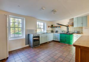 a kitchen with green cabinets and a tile floor at Three Ash Farm in Bungay