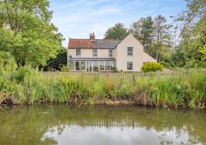 a white house with a pond in front of it at Three Ash Farm in Bungay