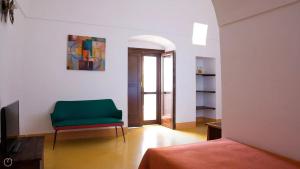 Habitación con silla verde y TV. en Dammusi Barone, en Pantelleria