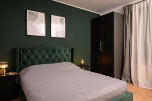 1 dormitorio con 1 cama verde y 2 cuadros en la pared en Cotroceni Accommodations, en Bucarest