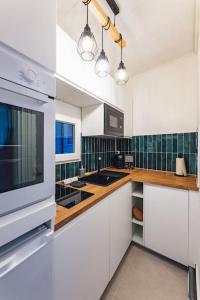una cocina con electrodomésticos blancos y azulejos verdes en Modern&Confort Fully Furnish Apartment ⭑ La Défense ⭑Champs Elysées⭑ RER A & L, en Maisons-Laffitte