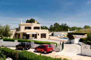 a house with two cars parked in front of it at Villa with Private Pool Near Benagil & Marinha Beach in Lagoa