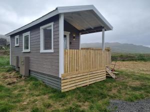 een kleine hut met een veranda op een veld bij Hvammur 6 with private hot tub 