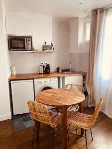 een keuken met een tafel en stoelen en een magnetron bij Comme à la maison-Porte de Paris in Pantin