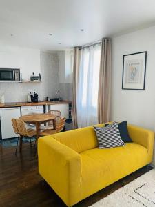 - un canapé jaune dans le salon avec une table dans l'établissement Comme à la maison-Porte de Paris, à Pantin