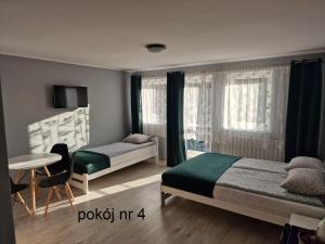 a bedroom with two beds and a table and a desk at Pokoje goscinne Maciej in Rozewie