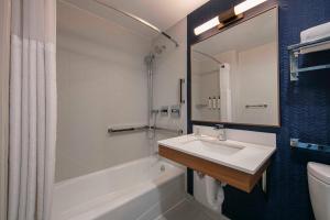 a bathroom with a sink and a tub and a mirror at Fairfield Inn by Marriott JFK Airport in Queens