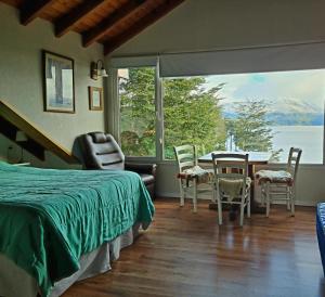 une chambre avec un lit, une table et des chaises dans l'établissement Puerto Esmeralda ESPECTACULAR DEPTO CON VISTA AL LAGO NAHUEL HUAPI, à Villa La Angostura