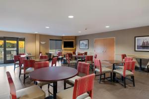 una sala da pranzo con tavoli, sedie e una tavola di Comfort Suites Suffolk - Chesapeake a Suffolk