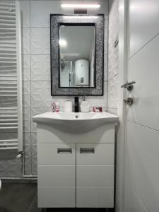 un bagno con un lavandino bianco e uno specchio di Apartman Jovana 2 a Sremska Mitrovica