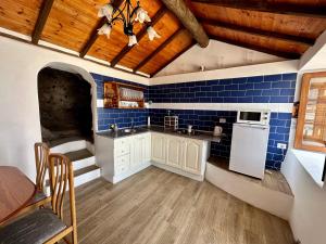 a kitchen with blue tiled walls and wooden ceilings at Chozos Cottage by VV Canary Ocean Homes in Las Cruces