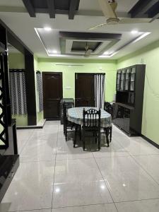 Sreenilayam Luxury Stay Homes في راجاموندري: غرفة طعام مع طاولة وكراسي وجدران خضراء