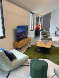 ein Wohnzimmer mit Stühlen und einem Flachbildfernseher in der Unterkunft Les Orangers in Saint-Tropez