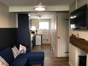 a living room with a blue couch and a kitchen at The Blue Porch Staithes in Staithes