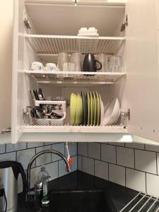 a kitchen sink with plates and dishes on a shelf at Studio in Kallio in Helsinki