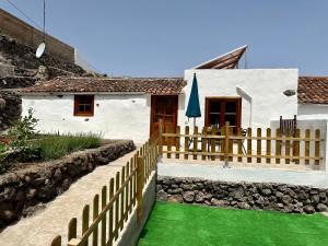 una casa blanca con valla y césped verde en Chozos Cottage by VV Canary Ocean Homes, en Las Cruces
