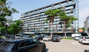 a parking lot with cars parked in front of a building at PALANGA DAUKANTO APARTAMENTAI in Palanga