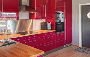 a red kitchen with red cabinets and a sink at Gorgeous Home In Berger With House Sea View in Svelvik