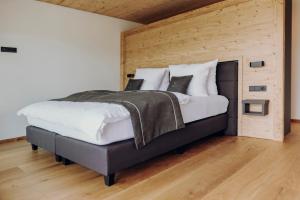 ein großes Bett in einem Zimmer mit einer Holzwand in der Unterkunft Platzhirsch Ofterschwang in Ofterschwang