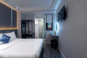 sypialnia z białym łóżkiem i telewizorem w obiekcie Ruby Saigon Hotel - Ben Thanh w Ho Chi Minh