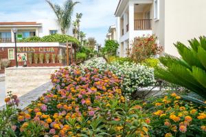 a garden of flowers in front of a building at Aktea Beach Village in Ayia Napa