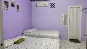 two twin beds in a bedroom with purple walls at Pousada Carimbó in Fortaleza