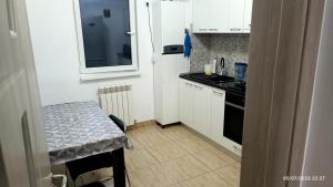 a small kitchen with a table and a white refrigerator at Natural House in Constanţa