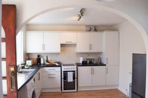 a white kitchen with white cabinets and an archway at Westcroft 6 Withnoe Terrace in Torpoint +11 photos