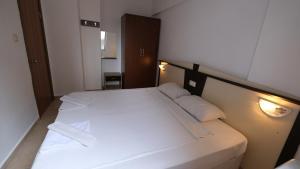 Schlafzimmer mit einem Bett mit weißer Bettwäsche und Kissen in der Unterkunft AGORA APART OTEL ALANYA in Alanya