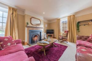 a living room with a fireplace and purple furniture at Abbey Farm House in St Bees