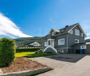 une grande maison grise avec une montagne en arrière-plan dans l'établissement Aalesund Holiday Home 4 Bedroom, à Ålesund