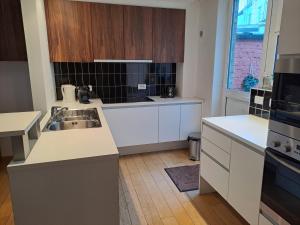 een keuken met witte werkbladen en een wastafel bij bel etage woning in Gent
