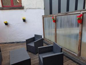 een patio met zwarte stoelen en bloemen op een hek bij bel etage woning in Gent