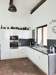 una cocina con armarios blancos y un reloj en la pared en splendide maison catalane renovee avec grande terrasse et garage, en Torreilles