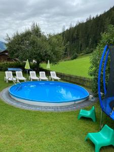 una piscina en un patio con sillas y un columpio en Gästehaus Hochwimmer, en Hollersbach im Pinzgau