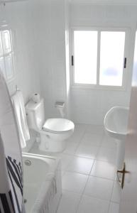 a white bathroom with a toilet and a sink at Hotel Abrego Reinosa in Reinosa