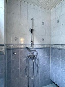 een douche in een badkamer met blauwe tegels bij Kapteeninmökki in Naantali