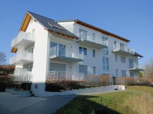 ein weißes Apartmenthaus mit Balkon und Hof in der Unterkunft Golf & Wellness Suite Bad Bellingen Apartment 5-9 in Bad Bellingen