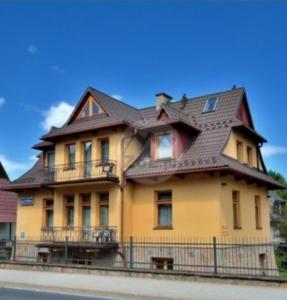a large yellow house with a brown roof at Willa nad Potokiem in Zakopane