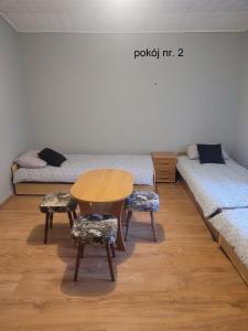 a room with two beds and a table and two chairs at Pokoje goscinne Maciej in Rozewie