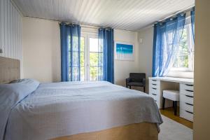 a bedroom with a bed and a desk and windows at Exclusive tranquil villa by the sea, boat available in Drottningskär