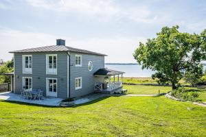 a house on a lawn with a view of the water at Exclusive tranquil villa by the sea, boat available in Drottningskär